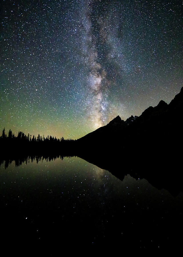 Milky Way rising above the silhouetted Teton Range and reflecting in String Lake at night